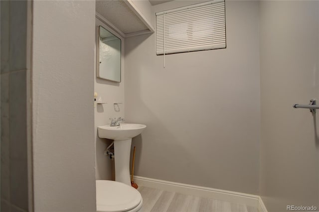 bathroom featuring a sink, baseboards, toilet, and wood finished floors