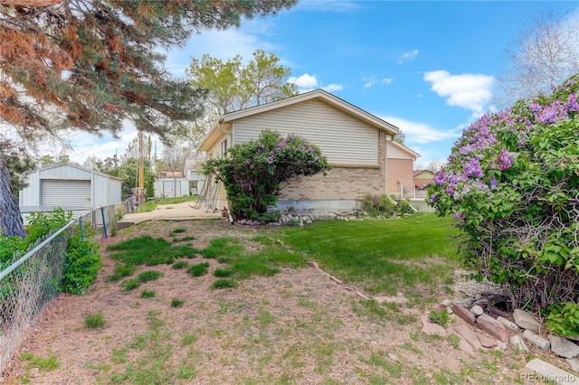 view of yard featuring an outbuilding, a detached garage, and fence