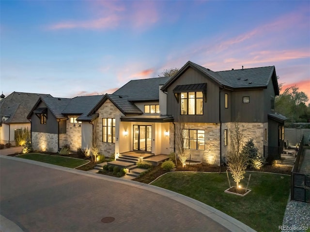 view of front of house featuring board and batten siding, a yard, and stone siding
