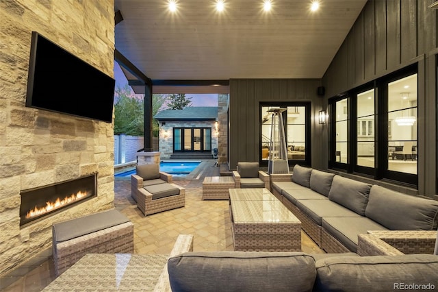 view of patio / terrace with a fenced in pool, an outdoor living space with a fireplace, and french doors