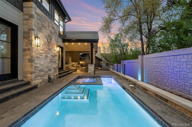pool at dusk featuring entry steps, an outdoor living space, a hot tub, and an outdoor pool