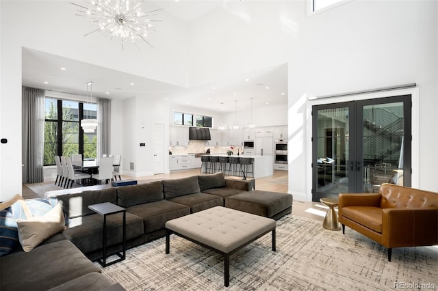 living room featuring a notable chandelier, french doors, recessed lighting, baseboards, and a towering ceiling
