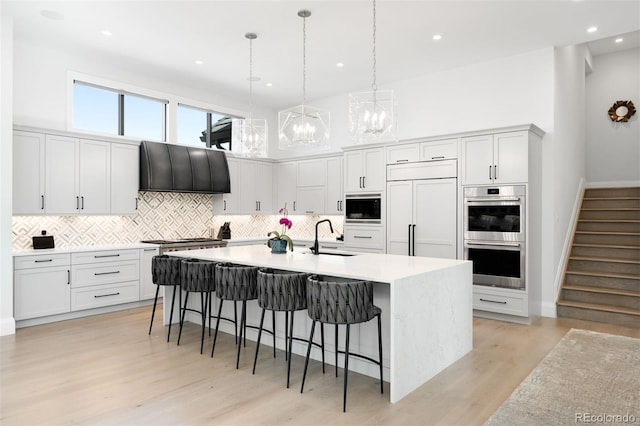 kitchen with a breakfast bar, a sink, ventilation hood, built in appliances, and backsplash