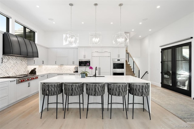 kitchen with backsplash, a sink, white cabinets, an inviting chandelier, and built in appliances