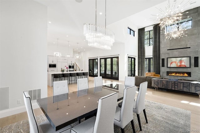 dining area with a wealth of natural light, a high ceiling, light wood-style flooring, and a chandelier