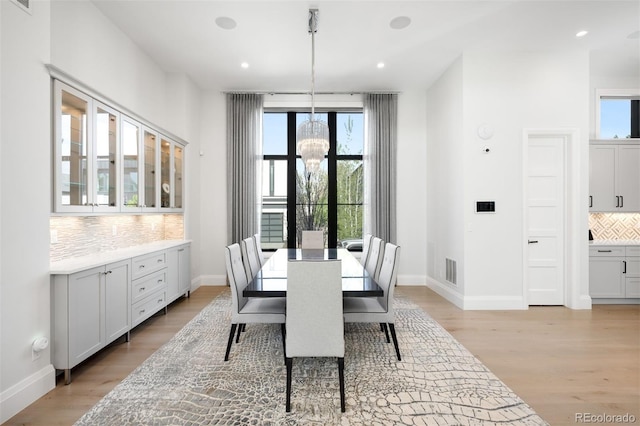 dining space with light wood-style floors, baseboards, an inviting chandelier, and visible vents