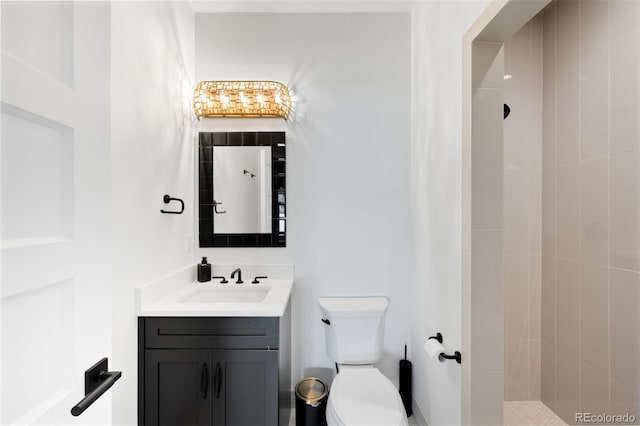 bathroom featuring vanity, a tile shower, and toilet