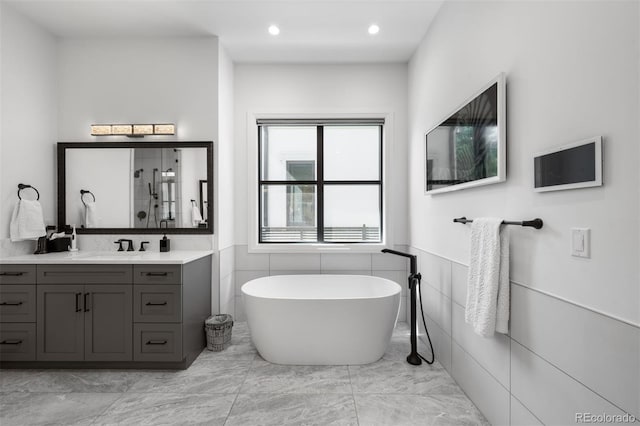 full bath with walk in shower, a freestanding bath, vanity, marble finish floor, and a wainscoted wall