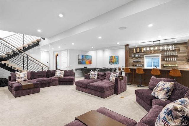 living area featuring decorative columns, light colored carpet, stairs, indoor bar, and recessed lighting