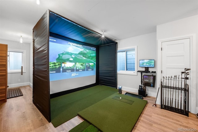 rec room with baseboards, golf simulator, and wood finished floors