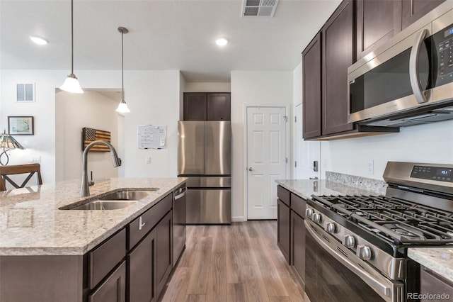 16841 Askins Loop Unit 101, Parker, CO 80134 - kitchen featuring appliances with stainless steel finishes, dark brown cabinets, light wood-style flooring, light stone counters, and recessed lighting