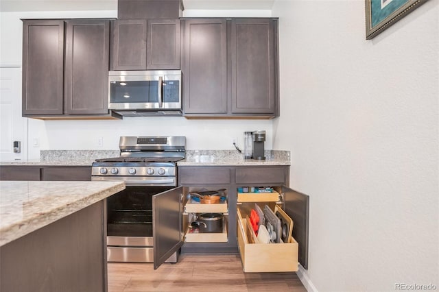 16841 Askins Loop Unit 101, Parker, CO 80134 - kitchen with stainless steel appliances, light wood-style floors, dark brown cabinets, and light stone counters