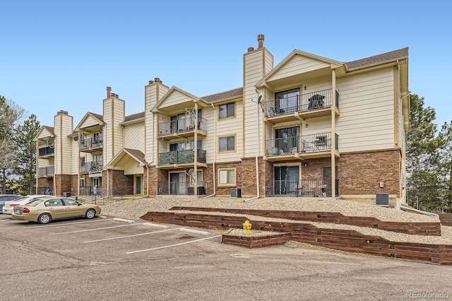 view of building exterior featuring uncovered parking and central AC