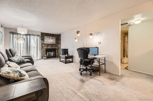 carpeted office space with a stone fireplace and a textured ceiling