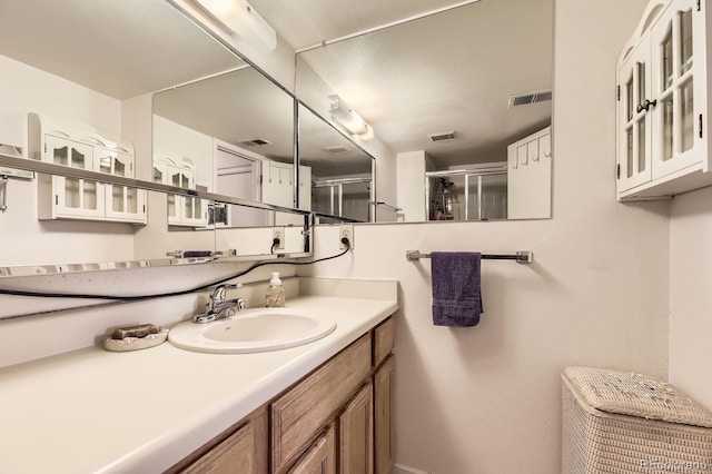 full bath featuring vanity, a stall shower, and visible vents