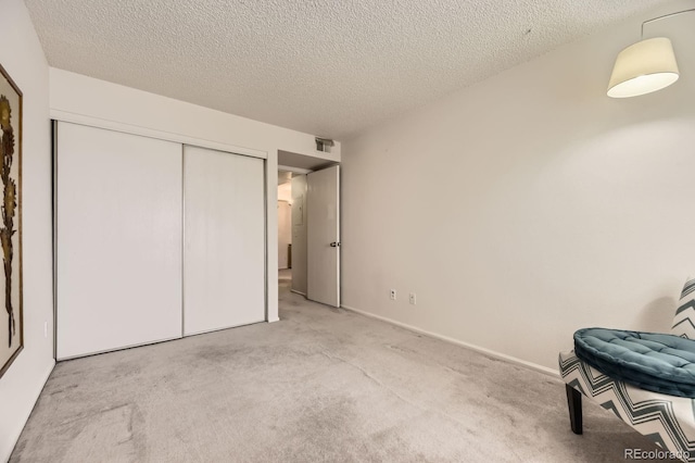 bedroom featuring carpet floors, a textured ceiling, baseboards, visible vents, and a closet