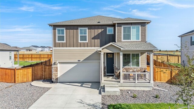 4125 Marble Dr, Longmont, CO 80504 - view of front of property with covered porch, concrete driveway, stone siding, an attached garage, and fence