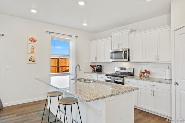 4125 Marble Dr, Longmont, CO 80504 - kitchen featuring appliances with stainless steel finishes, a sink, decorative backsplash, an island with sink, and white cabinetry