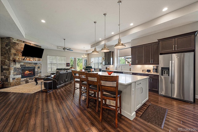 kitchen with a stone fireplace, dark hardwood / wood-style floors, stainless steel refrigerator with ice dispenser, and dark brown cabinetry