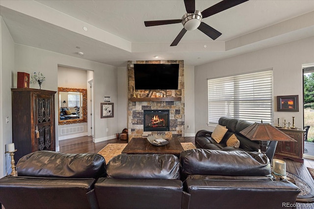 living area featuring baseboards, visible vents, a raised ceiling, wood finished floors, and a fireplace