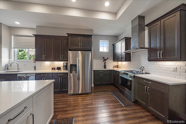 kitchen featuring dark hardwood / wood-style floors, stainless steel appliances, wall chimney range hood, tasteful backsplash, and sink