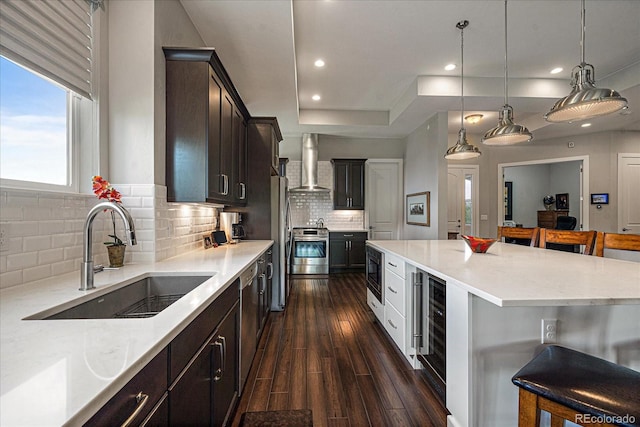 kitchen featuring stainless steel appliances, sink, tasteful backsplash, a center island, and wall chimney exhaust hood