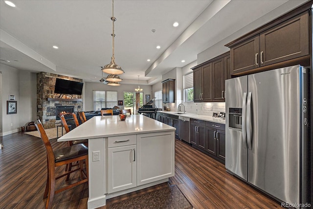 kitchen featuring open floor plan, light countertops, appliances with stainless steel finishes, a center island, and decorative light fixtures