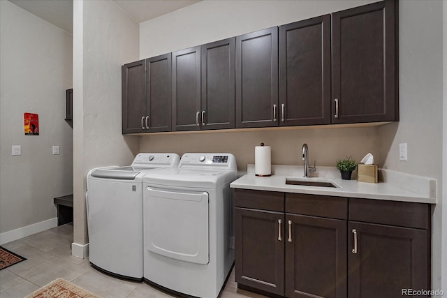 laundry room with light tile patterned floors, sink, cabinets, and washing machine and dryer