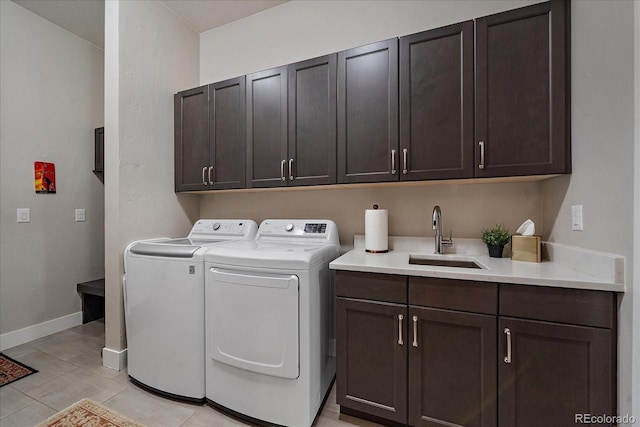 washroom featuring light tile patterned floors, a sink, baseboards, washer and dryer, and cabinet space