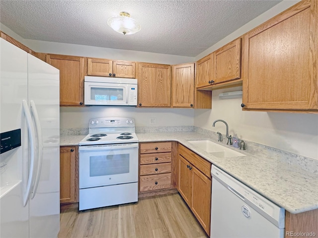 kitchen featuring white appliances, sink, light wood-type flooring, and a textured ceiling