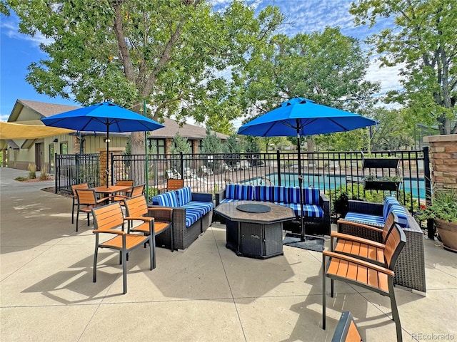 view of patio with a fenced in pool and an outdoor living space with a fire pit