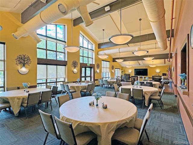 carpeted dining area with high vaulted ceiling