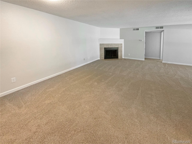 unfurnished living room featuring a textured ceiling, a tile fireplace, and carpet