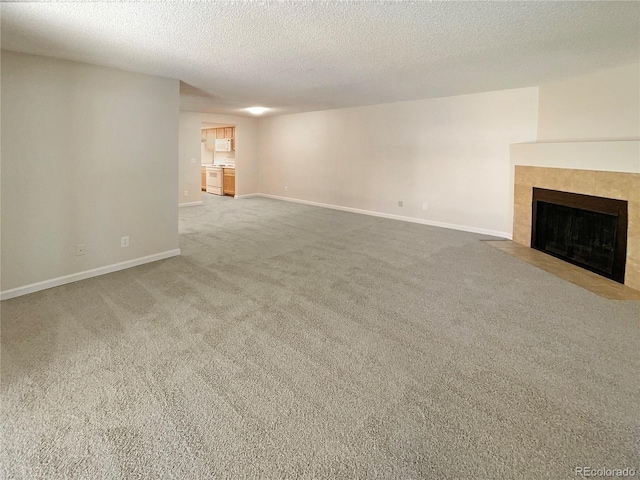 unfurnished living room featuring carpet, a tiled fireplace, and a textured ceiling