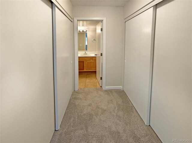 hall with light colored carpet and sink