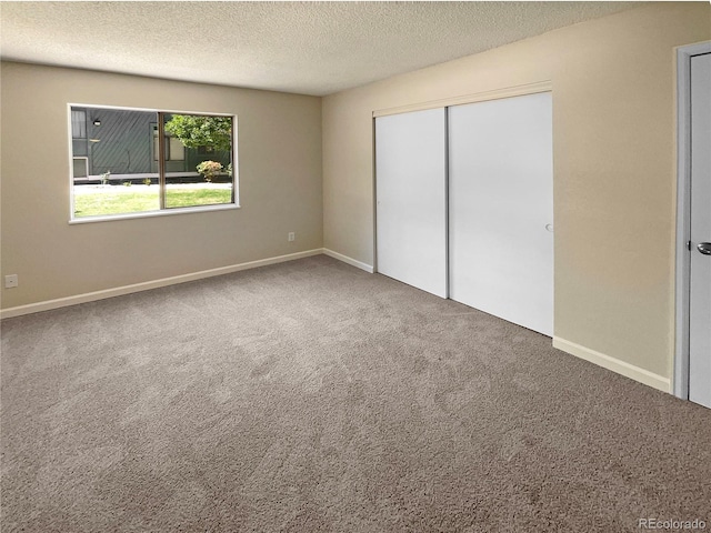 unfurnished bedroom with a textured ceiling, a closet, and carpet