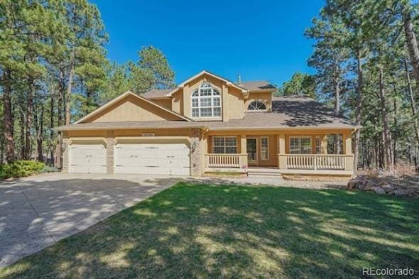 view of front of home with driveway, a garage, a front lawn, stucco siding, and covered porch