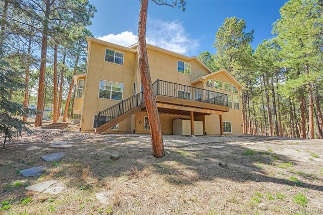 back of house with a garage, a deck, stairway, and stucco siding