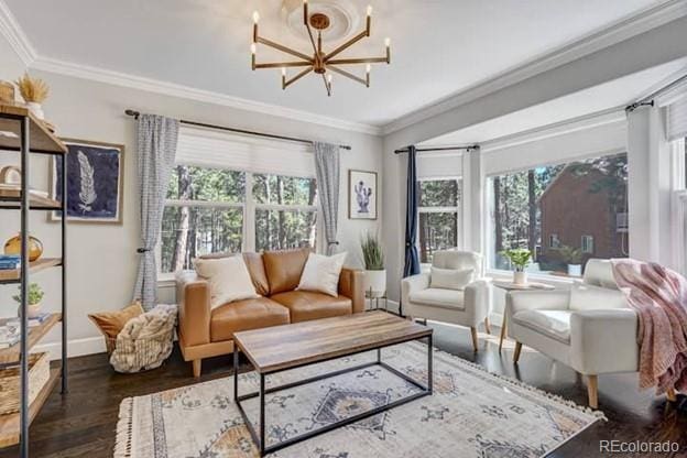 living area featuring crown molding, wood finished floors, a chandelier, and baseboards