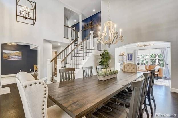 dining area featuring a chandelier, stairway, a high ceiling, baseboards, and arched walkways
