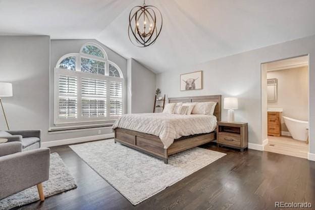 bedroom with vaulted ceiling, a chandelier, baseboards, dark wood-type flooring, and connected bathroom