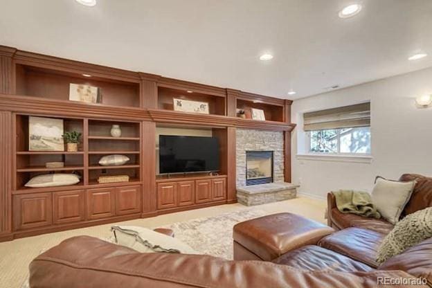living room with carpet, recessed lighting, and a stone fireplace