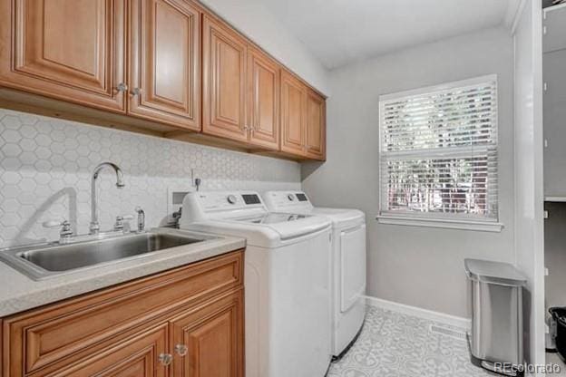 laundry area featuring washing machine and clothes dryer, cabinet space, and baseboards