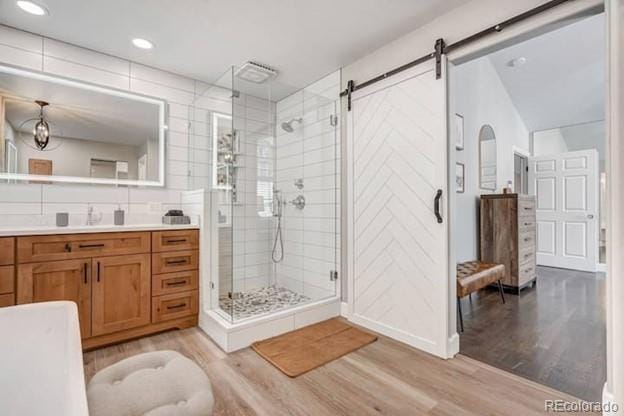 bathroom featuring wood finished floors, a shower stall, vanity, and recessed lighting