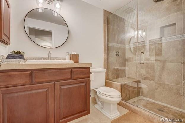 bathroom with toilet, a stall shower, tile patterned flooring, and vanity