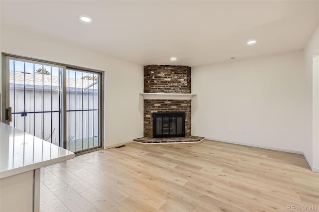 unfurnished living room featuring a fireplace and light hardwood / wood-style floors