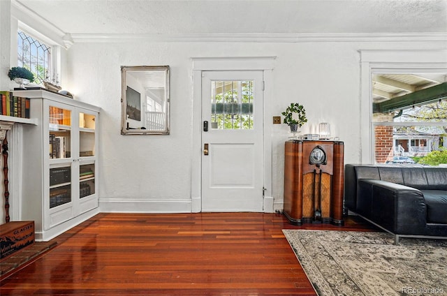 entrance foyer featuring crown molding, wood-type flooring, a textured ceiling, and a healthy amount of sunlight
