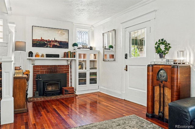 living room with a textured ceiling, ornamental molding, hardwood / wood-style flooring, and a fireplace