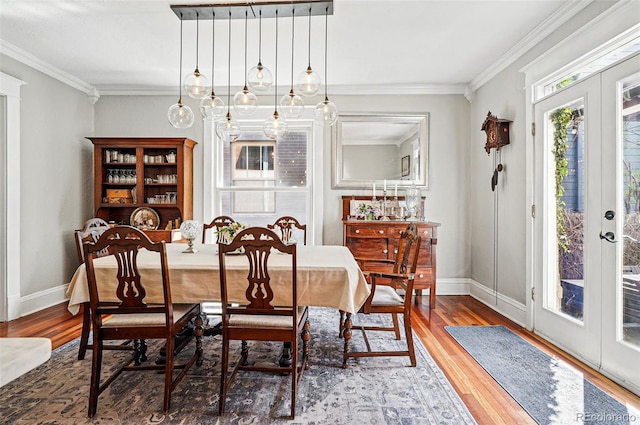 dining room featuring crown molding, baseboards, wood finished floors, and french doors