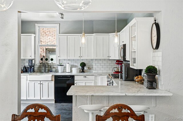 kitchen with a textured wall, a sink, dishwasher, stainless steel microwave, and decorative backsplash